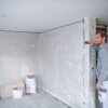 Bosch 50m Laser Measure - Site Application Worker using a Bosch 50m laser measure to calculate room dimensions on a construction site.