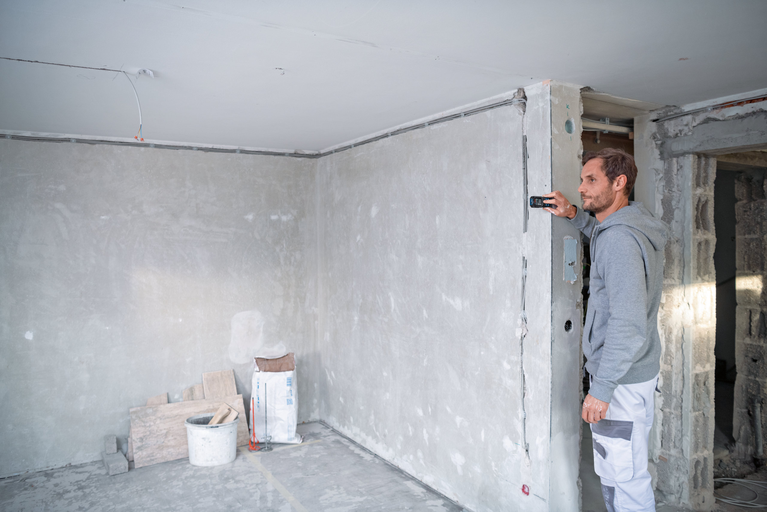 Bosch 50m Laser Measure - Site Application Worker using a Bosch 50m laser measure to calculate room dimensions on a construction site.