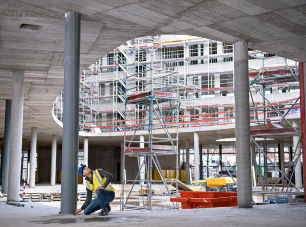 Bosch 50m Laser Measure - Vertical Measurement Measuring vertical distance with a high-visibility green beam laser on a large scale construction project.